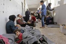 Des civils syriens ayant fui les dernières zones rebelles dans la Ghouta orientale près de Damas assis à même le sol dans un centre d'accueil du gouvernement syrien à Adra, le 20 mars 2018