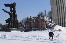 Un employé communal dégage la neige devant un monument de l'époque soviétique à Kiev célébrant l'union de la Russie et l'Ukraine, le 2 mars 2018