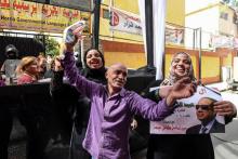 Des Egyptiens dansent dans une rue du quartier de Abdine, dans le centre du Caire, en arborant un poster à la gloire du président Abdel Fattah al-Sissi le 26 mars 2018 au premier jour de l'élection pr