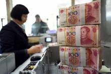 Une employée compte des billets de 100 yuan (15 USD) en Chine, dans une banque de Lianyungang dans la province du Jiangsu (est), le 7 janvier 2016