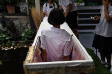 Une adolescente thaïlandaise est installée dans un cercueil du Café de prise de conscience de la mort à Bangkok, le 30 mars 2018
