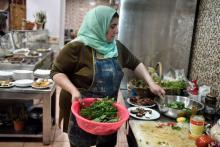 Une réfugiée d'Irak prépare des plats dans la cuisine du restaurant "Roots, farm to table" à Athènes, le 9 mars 2018 avec des légumes récoltés dans une ferme par d'autres réfugiés