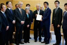 Le Premier ministre japonais Shinzo Abe (3e D) reçoit une pétition de Shigeo Iizuka (C) responsable d'un groupe de familles de Japonais enlevés par la Corée du Nord, aux côtés de Sakie Yokota (4e G), 
