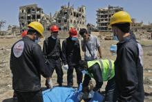 Un secouriste ouvre un sac mortuaire pour montrer un corps exhumé d'une fosse commune à Raqa, ancien bastion du groupe Etat islamique (EI) dans le nord de la Syrie, le 23 avril 2018