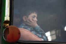 Un enfant lance un regard par la vitre d'un bus évacuant des rebelles de Jaich al-Islam et de leurs familles de Douma, ultime poche rebelle dans la Ghouta orientale le 12 avril 2018