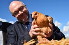 Le ministre français de l'Agriculture Stéphane Travert tient un poulet label rouge lors de sa visite dans une ferme de Trangé, dans le nord-ouest de la France, le 30 mars 2018