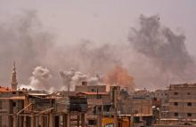 D'épais nuages de fumée se dégagent d'un quartier du sud de la capitale syrienne Damas après des frappes du régime visant le groupe Etat islamique dans le camp de Yarmouk et des quartiers avoisinants,