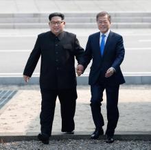 Kim Jong Un et Moon Jae-in traversent la Ligne de démarcation militaire qui divise la péninsule coréenne, le 27 avril 2018 à Panmunjom