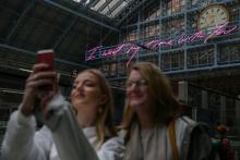 Des usagers se prennent en selfie devant une oeuvre de Tracey Emin à la gare Saint-Pancras à Londres, le 11 avril 2018