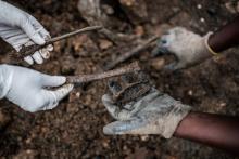 Une photo prise le 30 avril 2018 montre des experts en train de ramasser des ossements humains sur un site de charnier pendant le génocide au Rwanda en 1994 près de Kigali