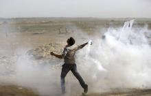 Un Palestinien renvoie une grenade lacrymogène lors d'affrontements avec l'armée israélienne dans la bande de Gaza, le 18 mai 2018