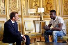 Le président français Emmanuel Macron discute avec le migrant malien Mamoudou Gassama, qui était dans la clandestinité en France et qui a escaladé à mains nues la façade d'un immeuble pour sauver un e