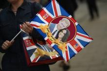 un visiteur porte un sac et un drapeau à l'effigie du prince Harry et de Meghan Markle dans les rues de Windsor le 17 mai 2018