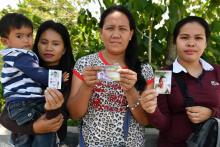 De G à D, Alma Tome, Evelyn Powao et Melgie Powao, montrent le 2 avril 2018 lors d'une interview avec l'AFP à Iligan (Philippines) les photos de leurs maris toujours disparus un an après le siège de M