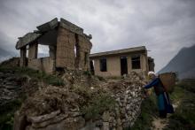 Une vieille dame passe le 21 avril 2018 devant son ancienne maison dans le hameau de Luobozhai (Sichuan) en Chine, dévasté par le séisme de 2008