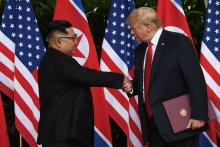 Le leader nord-coréen Kim Jong Un (g) et le président américain Donald Trump se serrent la main après avoir signé un document commun, le 12 juin 2018 à l'hôtel Capella, sur l'île de Sentosa, à Singapo