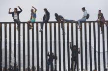 Des migrants qui ont participé à la caravane des migrants escaladent la barrière entre la frontière mexicaine et les Etats-Unis, le 29 avril 2018 à San Ysidro, en Californie