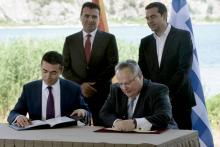 Le ministre macédonien des Affaires étrangères Nikola Dimitrov (g) et son homologue grec Nikos Kotzias signent l'accord sur le nom de Macédoine suèr les rives grecques du lac Prespes, le 17 juin 2018
