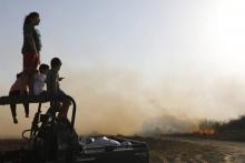 Des enfants israéliens face au feu dans un champ, provoqué par un cerf-volant incendiaire lancé de la bande de Gaza sur le Kibboutz Beeri situé près de la frontière, le 5 juin 2018