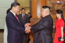 Photo fournie le 21 juin 2018 par l'agence nord-coréenne Kcna du leader nord-coréen Kim Jong Un accueilli par le président chinois Xi Jinping (g) à son arrivée à Pékin