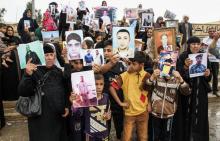 Photo prise le 13 avril 2018 montrant des Irakiennes brandissant des portraits de leurs proches disparus à Mossoul après la libération de cette ville du nord de l'Irak des jihadistes du groupe Etat is