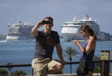 Un touriste prend un selfie avec au large des paquebots de croisière à Palma de Majorque, le 12 août