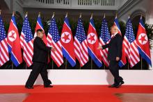 Le leader nord-coréen Kim Jong Un (g) et le président américain Donald Trump se dirigent l'un vers l'autre pour se serrer la main, le 12 juin 2018 à l'hôtel Capella sur l'île de Sentosa, à Singapour