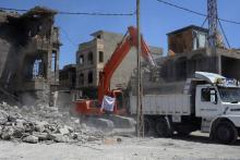 Des camions participent à la campagne de déblaiement de la vieille ville de Mossoul, entièrement détruite par les combats contre le groupe Etat islamique (EI), le 27 juin 2018