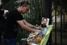 Un membre de la communauté chinoise pose des fleurs à côté d'une photo du couturier, Chaolin Zhang , tué lors d'une agression à Aubervilliers, à l'occasion du premier anniversaire de sa mort, le 7 aoû