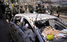 Une patrouille de la police militaire brésilienne passe devant une voiture criblée de balles dans la favela de Jacarezinho de Rio, le 18 janvier 2018