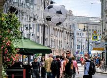 (FILES) In this file photo taken on May 24, 2018 people walk past a cafe decorated with a football-themed installation featuring a goal net and a ball in Moscow.