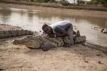 Un garçon s'allonge sur le dos d'un crocodile, le 19 mai 2018 à Bazoulé, au Burkina Faso