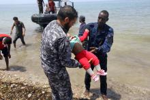 Des membres de la sécurité libyenne portent le corps d'un bébé dans la ville d'al-Hmidiya, après le naufrage au large de la Libye d'une embarcation de migrants dont 100 sont toujours portés disparus, 
