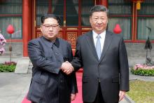 Photo fournie le 27 mars 2018 par l'agence nord-coréenne Kcna du leader nord-coréen Kim Jong-Un (g) et du président chinois Xi Jinping à Pékin