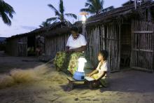 Yollande Randrianambinina, 53 ans, recoud un filet de pêche, éclairée grâce à l'énergie solaire installée dans son village d'Ambakivao, le 23 avril 2018 à Madagascar