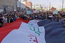 Des Irakiens tiennent le drapeau national et scandent des slogans lors d'une manifestation contre le chômage et le manque de services à Najaf (centre), le 20 juillet 2018
