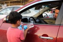 Un garçon irakien essaye de vendre des bouteilles d'eau dans une rue de Mossoul, où des enfants orphelins errent pour mendier ou vendre des objets futiles pour survivre, un an après la reprise par l'a