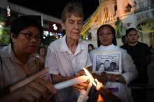 La religieuse australienne Patricia Fox allume un cierge lors d'une veillée de prière pour des prêtres catholiques assassinés, à Manille le 18 juin 2018 après l'annulation d'un arrêté d'expulsion qui 