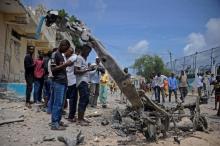 Des jeunes somaliens regardent et photographient la carcasse d'un véhicule des insurgés shebab qui a explosé près du palais présidentiel à Mogadiscio le samedi 14 juillet 2018