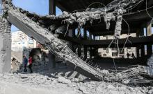 Des Palestiniens devant un immeuble détruit par des frappes aériennes israéliennes, le 15 juillet 2018 à Gaza