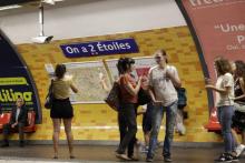 Des passagers du métro de Paris marchent devant l'affiche "Deschamps - Elysées Clemenceau", référence au nom de l'entraîneur de l'équipe de France de football Didier Deschamps, à la station de Champs 