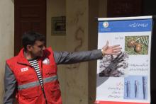 Un membre du Croissant-Rouge explique les dangers des mines antipersonnel à des habitants d'Abbaspur, le 22 février 2018 au Cachemire pakistanais