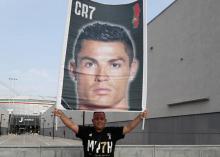 Un supporteur de la Juventus brandit un portrait de Cristiano Ronaldo devant le centre où le footballeur doit passer une visite médicale, à Turin (Italie) le 16 juillet 2018