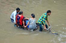 Des habitants traversent une route inondée après de fortes pluies à Mathura, dans l'Etat indien de l'Uttar Pradesh, le 26 juillet 2018.