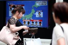 Des piétons passent devant un écran de télévision diffusant des informations sur l'exécution de six membres de la secte Aum Vérité Suprême, le 26 juillet 2018 à Tokyo