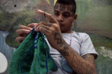 Un ex-membre du gang Barrio 18 tricote un bonnet lors d'un atelier tricot à la prison de San Francisco Gotera, le 16 juillet 2018 au Salvador