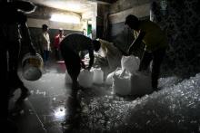 Des ouvriers indiens préparent des cubes de glace pour leur livraison aux clients dans une usine à Noida en banlieue de New Delhi, le 27 juin 2018