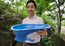 Un responsable de la société japonaise Lixil présente la cuvette créée par l'entreprise pour réduire les problèmes sanitaires liés à l'absence de toilettes dans les pays en voie de développement, le 2