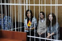 (g-d) Les "Pussy Riot" Nadejda Tolokonnikova, Iékaterina Samoutsevitch et Maria Alekhina derrière les barreaux, lors de leur procès à Moscou, le 23 juillet 2012
