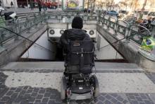 Une personne en fauteuil roulant devant une bouche de métro à Paris non accessible aux handicapés, en avril 2013